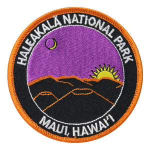 Round patch has name of Haleakalā National Park and Maui, Hawaiʻi embroidered around the edge of a scene depicting a purple sky with a rising gold sun and the sliver of a moon, over dark cinder cones rimmed in dawn light.