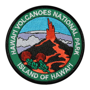 Round patch has name of Hawaiʻi Volcanoes National Park and Island of Hawaiʻi embroidered around the edge of a scene depicting a lava fountain erupting from a cinder cone, with the native Hawaiian ʻohiʻa lehua blossoms in the foreground and a snow-capped Mauna Kea under a blue sky in the background.