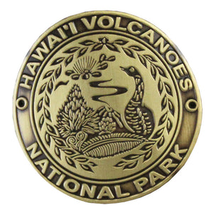 Metal medallion is 1.75 inches in diameter, gold, with engravings of a nēnē, a volcanic plume and native plants.