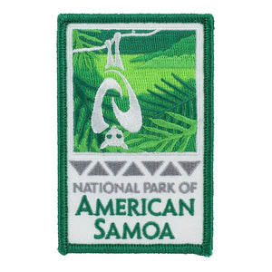 Rectangular green and white patch shows fruit bat/flying fox and rainforest logo of the National Park of American Samoa and park name in green on a white background.