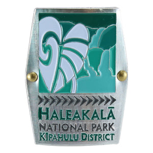Rectangular green, silver and white hiking medallion shows the taro plant and waterfalls of Haleakalā National Historical Park on Maui.