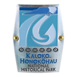 Rectangular blue and white hiking medallion shows fishhook and fishpond logo of Kaloko-Honokōhau National Historical Park on Hawaiʻi Island.