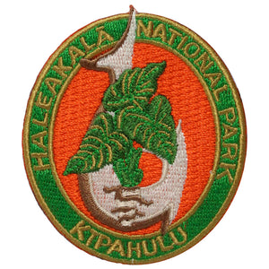 Oval patch has the name Haleakalā National park embroidered in green around a red field showing a taro/kalo plant growing through a traditional Hawaiian fish hook. The word "Kīpahulu" is embroidered on the bottom of the oval.