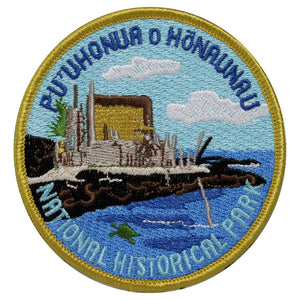 Round patch has name of Puʻuhonua o Hōnaunau National Historical Park embroidered around the edge of a scene depicting Hale o Keawe, kiʻi (tiki), and the waters of the bay with a green sea turtle swimming.
